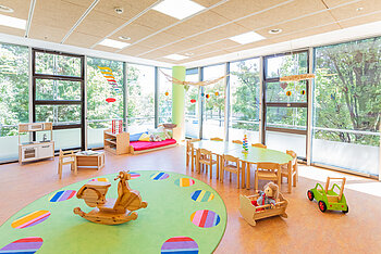 Gruppenraum mit Tisch und Spielgeräten der Kita Kleine Riesen München Schwabing