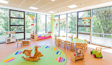 Gruppenraum mit Tisch und Spielgeräten der Kita Kleine Riesen München Schwabing
