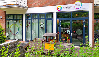 Kita Petits Géants Hamburg Lokstedt - Außenfläche mit Holzzug und Gebäude