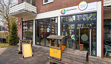 Kleine Riesen Hamburg Lokstedt - Außenfläche mit Holzzug und Gebäude