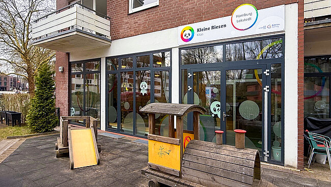 Kleine Riesen Hamburg Lokstedt - Außenfläche mit Holzzug und Gebäude