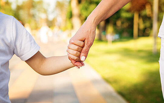 Hand von einer Person hält Kinderhand im Park