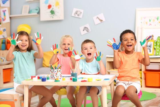 Vier glückliche Kinder zeigen ihre mit Farbe bemalten Hände