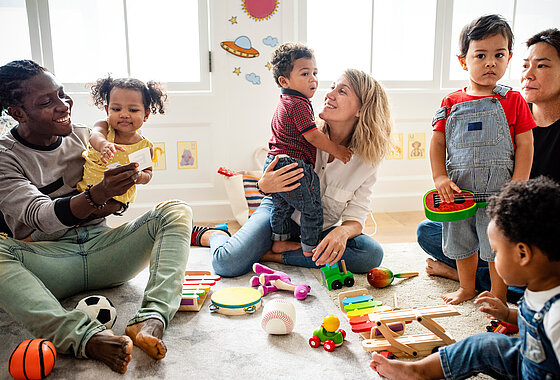 Eltern, Kinder und Erzieherinnen sitzen in einem Kreis - Partnerschaft - Kita